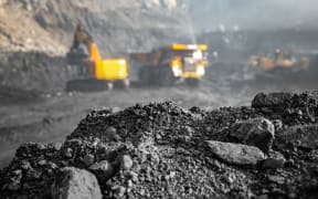 Coal open pit mine. In background blurred loading anthracite minerals excavator into large yellow truck.