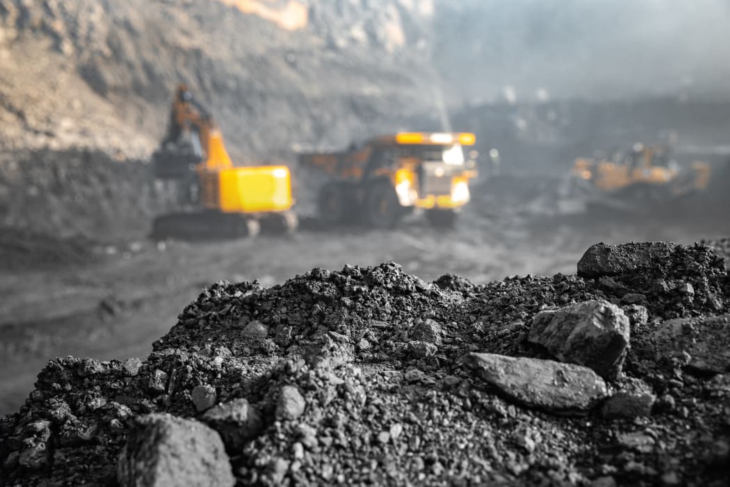 Coal open pit mine. In background blurred loading anthracite minerals excavator into large yellow truck.