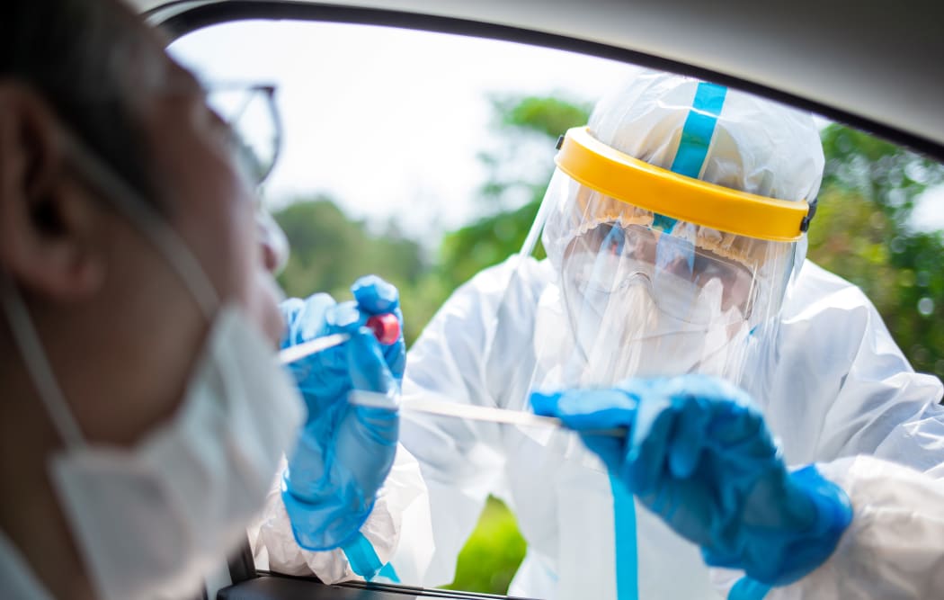 Coronavirus test - Medical worker taking a throat swab for coronavirus sample from a potentially infected elder man with the isolation gown or protective suits and surgical face masks