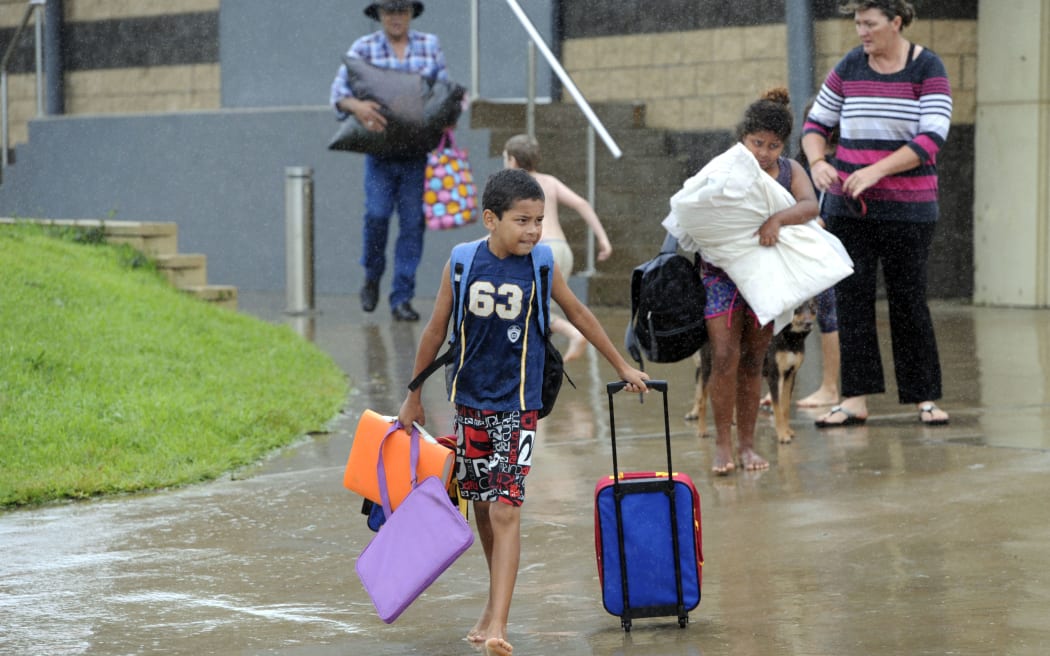Families leave the Cooktown evacuation centre after taking shelter overnight.
