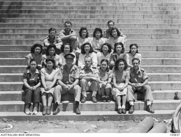 A group of men and women - the men in military uniform - sit on some steps.
