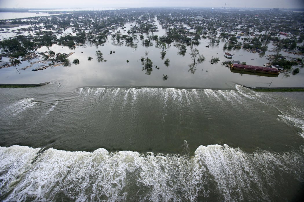 Water spills over a levee along the Inner Harbor Navigational Canal in the aftermath of Hurricane Katrina 30 August, 2005 in New Orleans.