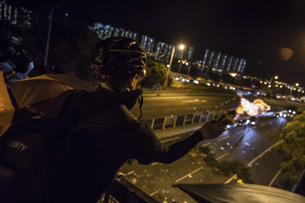 A protester throws a molotov cocktail to stop vehicles from passing through their road block beneath a bridge at the Chinese University of Hong Kong (CUHK) on November 15, 2019.