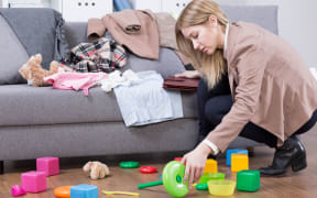 Young mother cleaning her kid's toys at home. Woman tired after work