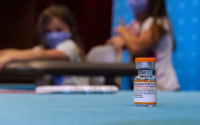 A vial of the new children's dose of the Pfizer-BioNTech Covid-19 vaccine sits in the foreground as children play in a hospital room at Hartford Hospital, Connecticut, US, 2 November 2021.