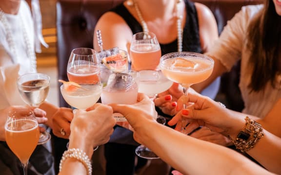 People clinking a variety of cocktail glasses together at a party