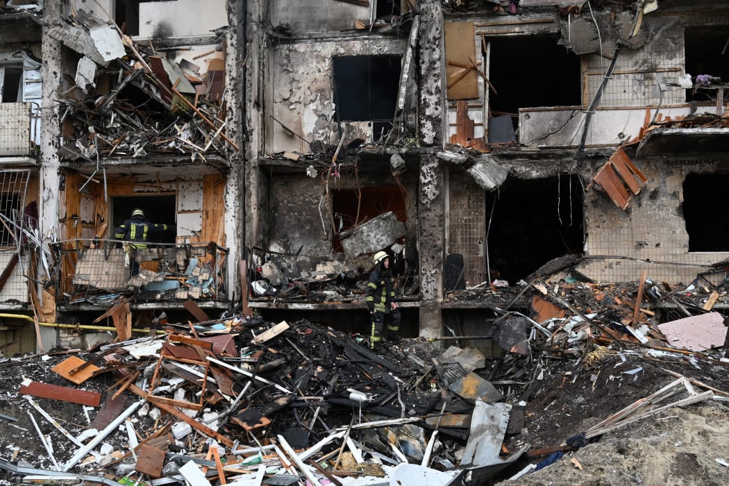 Firefighters work at a damaged residential building at Koshytsa Street, a suburb of the Ukrainian capital Kyiv, where a military shell allegedly hit, on February 25, 2022.