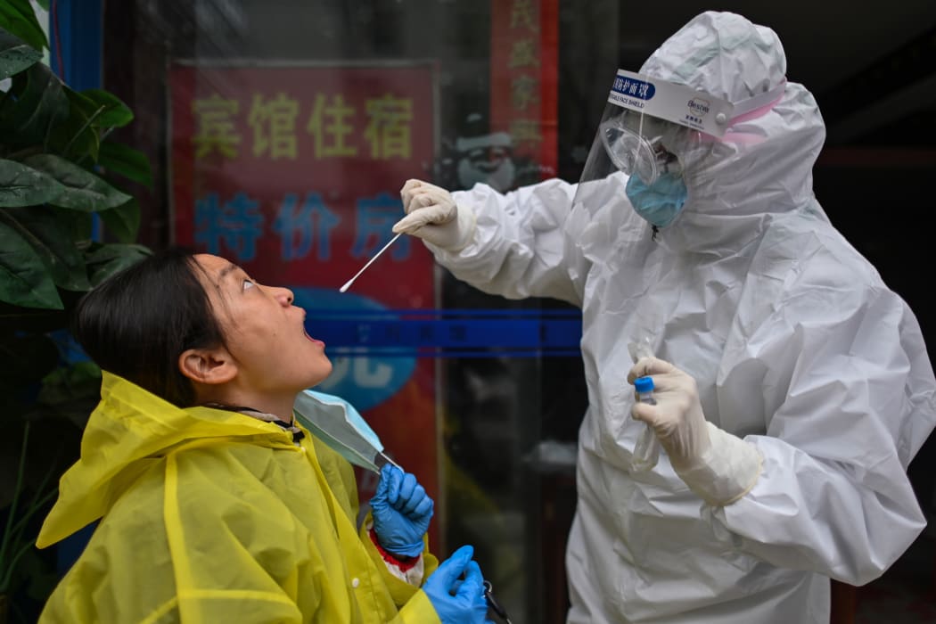 A medical worker takes a swab sample from a person to be tested for the COVID-19 novel coronavirus in Wuhan, China's central Hubei province on March 29, 2020, a day after travel restrictions into the city were eased following the outbreak.