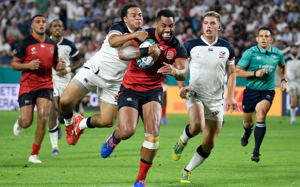 England's wing Joe Cokanasiga (C) is tackled by US prop David Ainuu (2L) as he runs to score a try  during the Japan 2019 Rugby World Cup Pool C match between England and the United States.