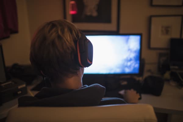 Teenage boy with headphones playing video game in dark bedroom. (Photo by CAIA IMAGE/SCIENCE PHOTO LIBRARY / NEW / Science Photo Library via AFP)