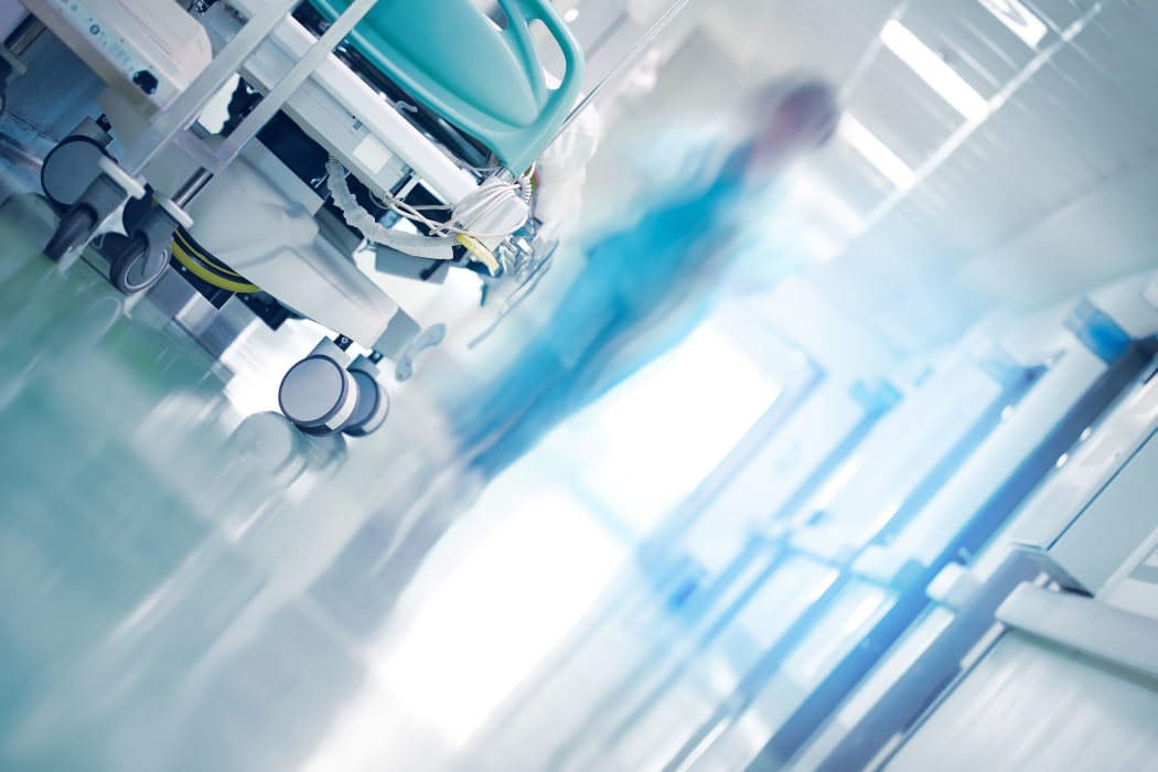 Medical bed in hospital hallway with professionals hurrying to the emergency case