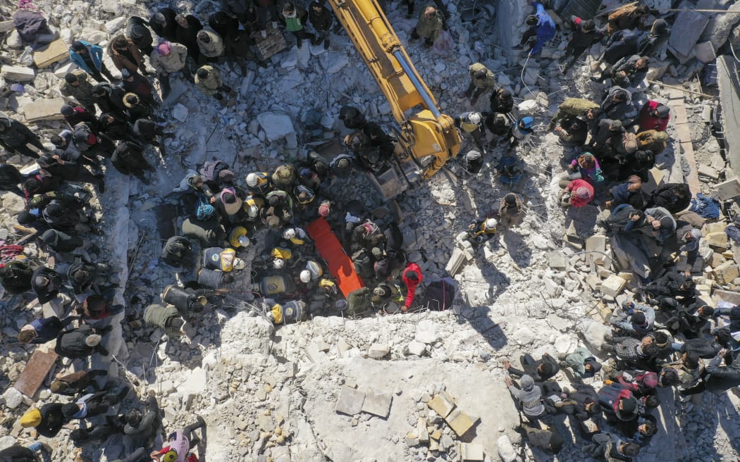An aerial picture shows rescuers searching the rubble of buildings for casualties and survivors in the village of Salqin in Syria's Idlib province following an earthquake, on February 7, 2023.