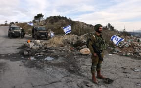 (FILES) In this file photo taken on December 30, 2021 Israeli soldiers guard the road leading to the Homesh Yeshiva (religious school), located at the former settlement of Homesh, west of the West Bank city of Nablus. - Israel's settler movement won a victory in the parliament on March 21, 2023 by overturning  a law banning them from residing in areas of the northern West Bank from which Jewish settlers were evacuated in 2005. (Photo by MENAHEM KAHANA / AFP)