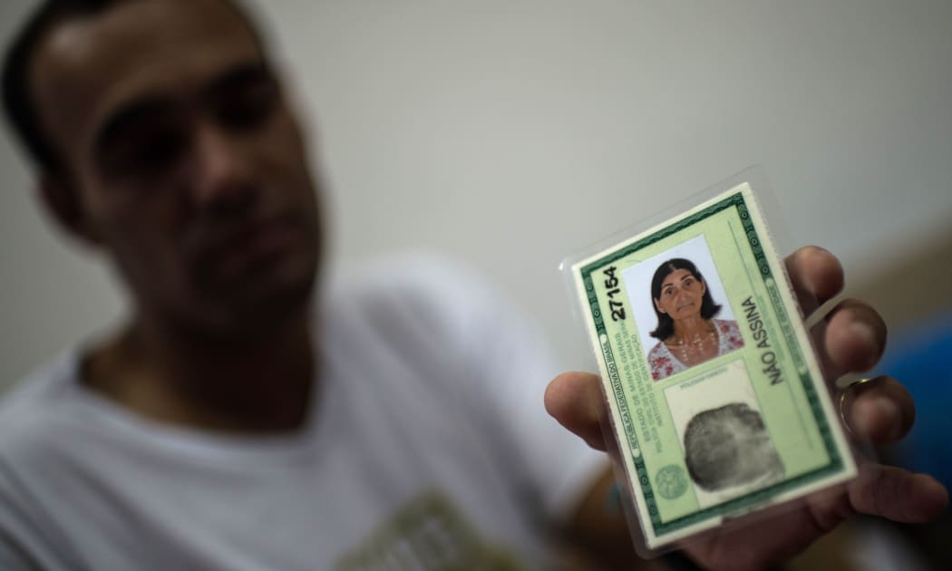 Marcello Jose Felicio, 30, shows the ID of his mother Maria "Gracita" who disapeared during the mudslide that buried their village, Bento Rodrigues, in Mariana, Brazil, on 8 november, 2015 AFP PHOTO / CHRISTOPHE SIMON