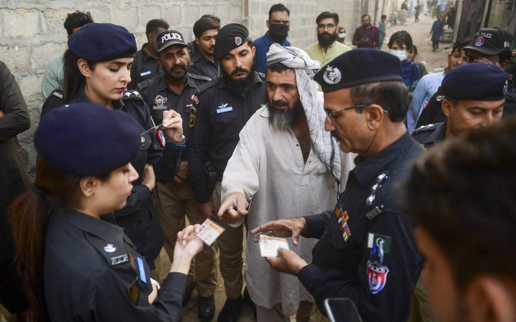 Police personnel check documents of Afghan refugees during a search operation to identify alleged illegal immigrants, on the outskirts of Karachi on November 17, 2023. More than 200,000 people have crossed from Pakistan into Afghanistan, Pakistani border officials said, the vast majority since an October ultimatum given to the 1.7 million Afghans Islamabad said were living illegally in the country. (Photo by Asif HASSAN / AFP)