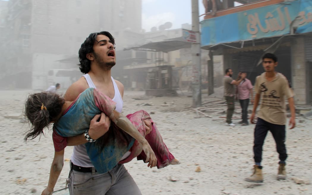 A man carries a girl injured in a reported barrel-bomb attack by government forces  in Kallaseh district in the northern city of Aleppo.
