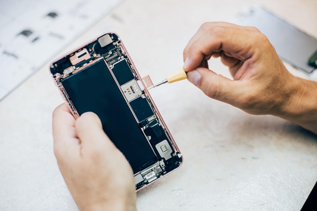 Technician repairs and inserts the sim memory card on the mobile phone in electronic smartphone technology service. Cellphone technology device maintenance engineer