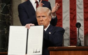 US President Donald Trump holds up an executive order that renames a wildlife sanctuary in honor of the late Jocelyn Nungaray, a 12 year-old girl who was murdered by two undocumented migrants, during an address to a joint session of Congress at the US Capitol in Washington, DC, on March 4, 2025. (Photo by Win McNamee / POOL / AFP)