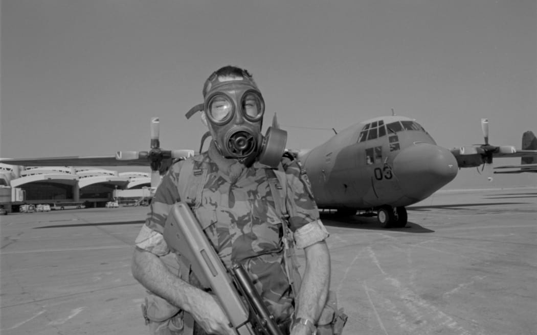 Operation Frescoe, Gulf War 1. Sergeant Phil Lane, wearing a gas mask and carrying a Steyer rifle, on security duty on the tarmac in front of No. 40 Squadron Hercules NZ7003. Believed to be at Riyadh, Saudi Arabia.