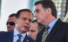 Brazilian President Jair Bolsonaro (R) listens to Sao Paulo's Governor Joao Doria while attending a military event in Sao Paulo, Brazil, on October 11, 2019.