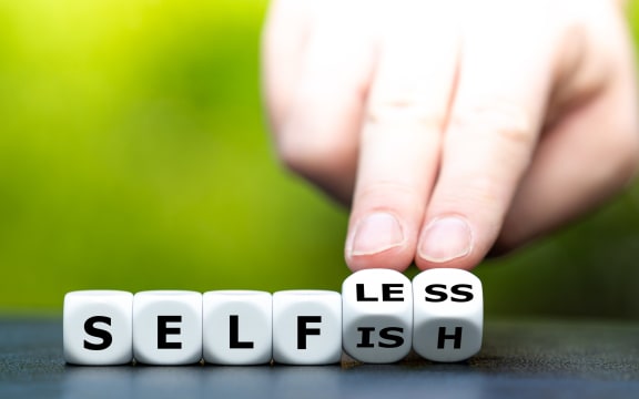 Hand turns dice and changes the word "selfish" to "selfless"No caption.