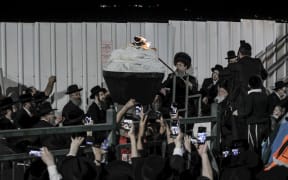 An Ultra-Orthodox Jewish rabbi lights up a bonfire at the grave site of Rabbi Shimon Bar Yochai at Mount Meron in northern Israel on 29 April, 2021, marking the anniversary of the death of the Talmudic sage about 1900 years ago.
