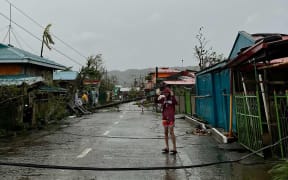 This handout taken and released on November 17, 2024 courtesy of Mayor Cesar Robles shows a resident standing past an uprooted electric post (background) in Panganiban town, Catanduanes province, after Super Typhoon Man-yi hit the province. - Super Typhoon Man-yi slammed into the Philippines' most populous island on November 17, with the national weather service warning of flooding, landslides and huge waves as the storm sweeps across the archipelago nation. (Photo by Handout / Mayor Cesar Robles / AFP) / -----EDITORS NOTE --- RESTRICTED TO EDITORIAL USE - MANDATORY CREDIT "AFP PHOTO / COURTESY OF MAYOR CESAR ROBLES" - NO MARKETING - NO ADVERTISING CAMPAIGNS - DISTRIBUTED AS A SERVICE TO CLIENTS