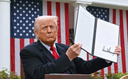 US President Donald Trump holds a signed executive order after delivering remarks on reciprocal tariffs during an event in the Rose Garden entitled “Make America Wealthy Again” at the White House in Washington, DC, on April 2, 2025. Trump geared up to unveil sweeping new “Liberation Day” tariffs in a move that threatens to ignite a devastating global trade war. Key US trading partners including the European Union and Britain said they were preparing their responses to Trump’s escalation, as nervous markets fell in Europe and America. (Photo by SAUL LOEB / AFP)