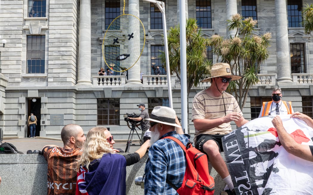 A protestor holds a small gallows with a representation of the Prime Minister in the noose.