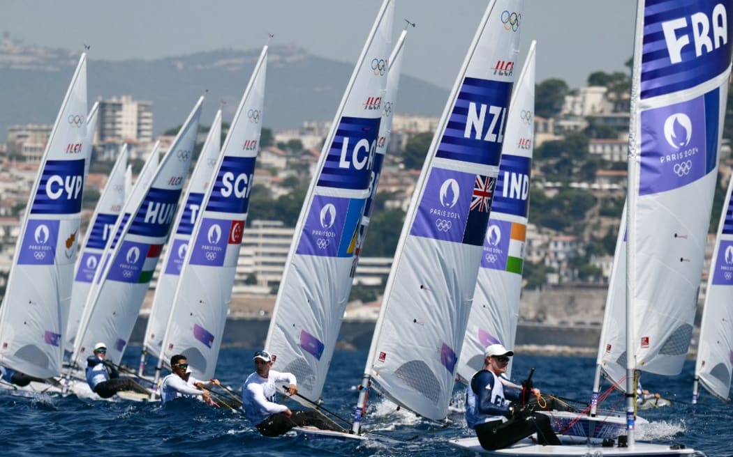 New Zealand's Thomas Saunders (C) and France's Jean-Baptiste Bernaz compete in race 1 of the men’s ILCA 7 single-handed dinghy event during the Paris 2024 Olympic Games sailing competition at the Roucas-Blanc Marina in Marseille on August 1, 2024. (Photo by Christophe SIMON / AFP)
