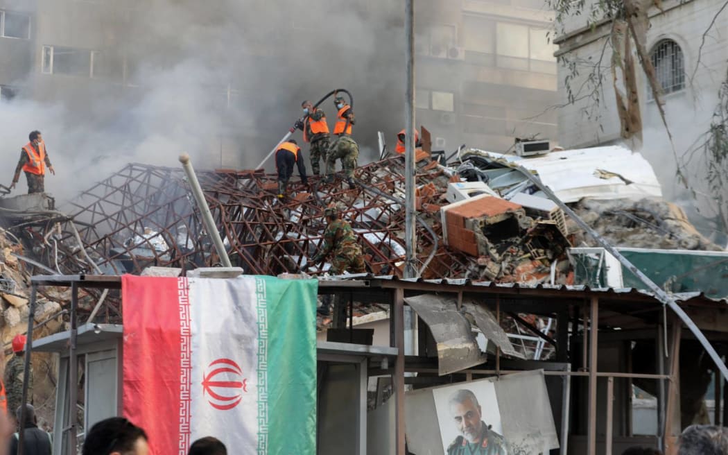 Emergency and security personnel extinguish a fire at the site of strikes which hit a building annexed to the Iranian embassy in Syria's capital Damascus, on 1 April, 2024. Syrian state media said Israeli strikes hit an Iranian consular annex in the capital on April 1, while a war monitor reported eight people were killed and Iranian state media said a senior commander of the powerful Islamic Revolutionary Guard Corps was among the dead, amid rising regional tensions due to the Gaza war. (Photo by LOUAI BESHARA / AFP)