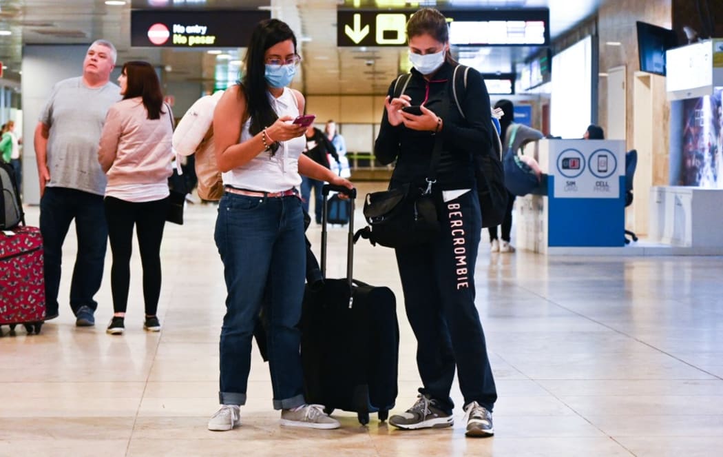 Passengers wearing protective masks wait at Madrid-Barajas airport, in Madrid, Spain.