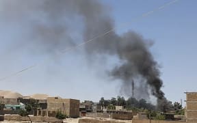 A smoke plume rises from houses amid ongoing fight between Afghan security forces and Taliban fighters in the western city of Qala-e-Naw, the capital of Badghis province, on 7 July 2021.