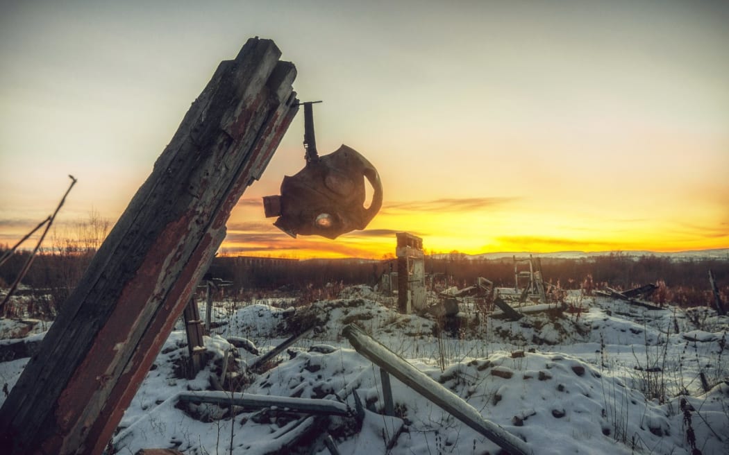 Nuclear winter.Old gas mask in the ruins. The remains of houses covered with snow at sunset