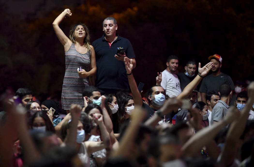 People celebrate in the street after Tunisian President Kais Saied announced the dissolution of parliament and Prime Minister Hichem Mechichi's government in Tunis.