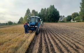Bob Mehrtens stands next to his tractor and a freshly ploughed field.