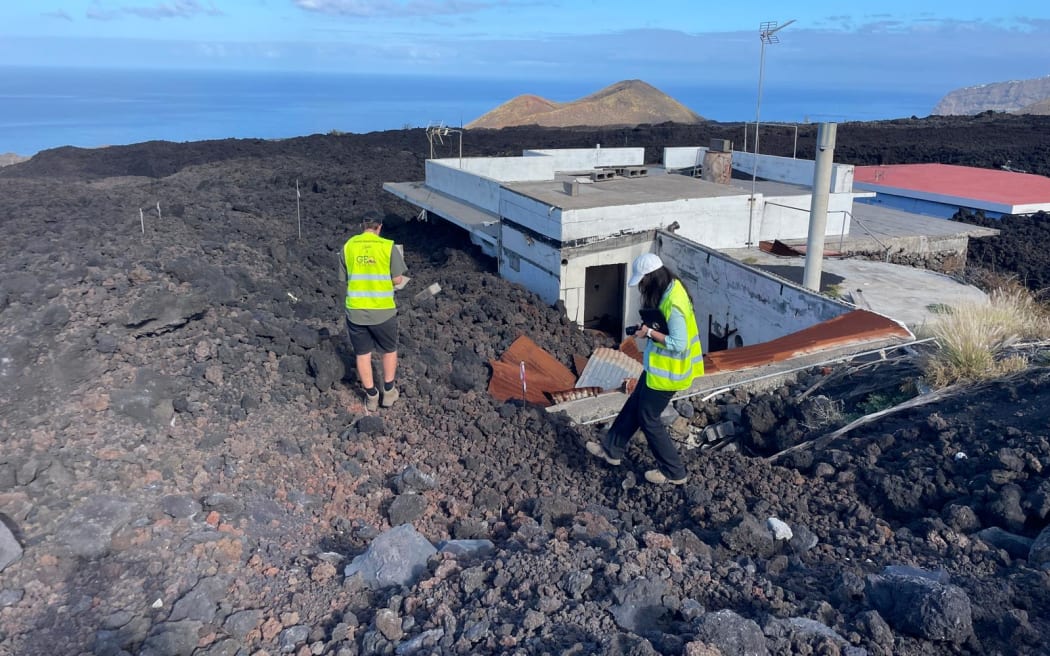 GNS scientists at a building that has been engulfed in lava.