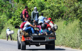 Hondurans get on vans and trucks during the exodus towards the US from San Pedro Sula