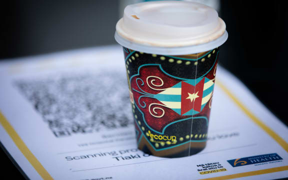 A takeaway coffee cup next to a QR code