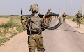 Israeli soldiers walk near the border with Gaza Strip in southern Israel on March 12, 2024, amid the ongoing battles between Israel and the Palestinian militant group Hamas. (Photo by Menahem KAHANA / AFP)