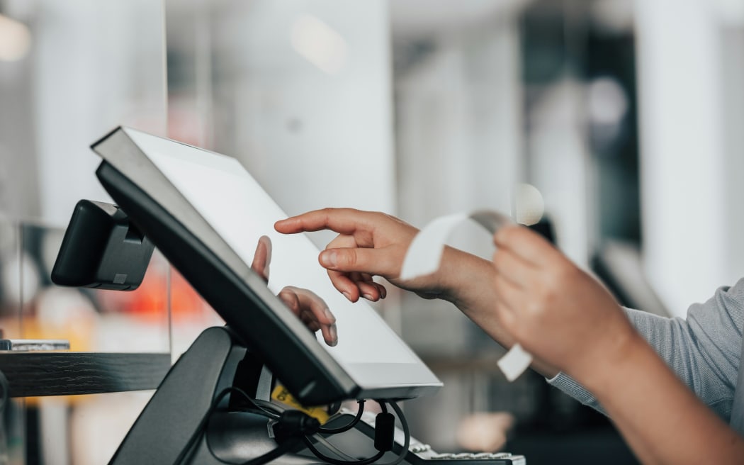 Someone holding a receipt and typing into a computer.