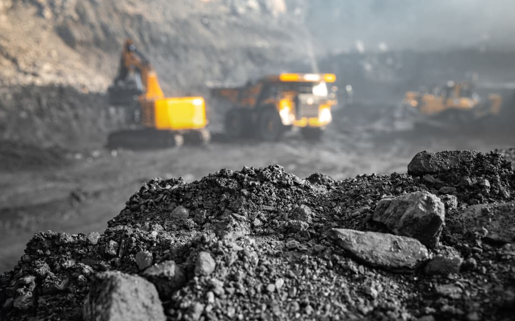 Coal open pit mine. In background blurred loading anthracite minerals excavator into large yellow truck.