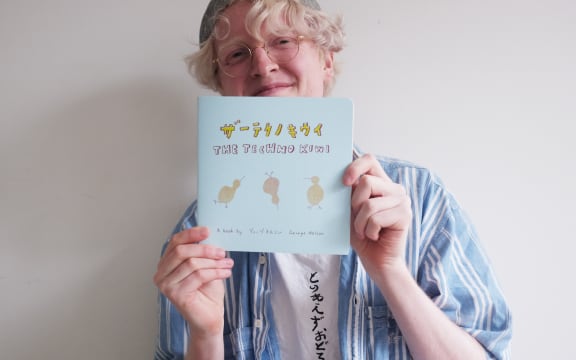 George Nelson holds a blue book he wrote called The Techno Kiwi