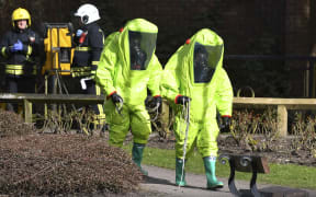 Members of the fire brigade in green biohazard suits work near the bench where a Russian former double-agent and his daughter were found.