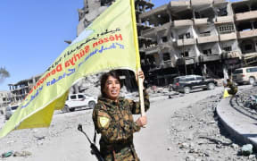 Rojda Felat, a Syrian Democratic Forces (SDF) commander, waves her group's flag at the iconic Al-Naim square in Raqqa.