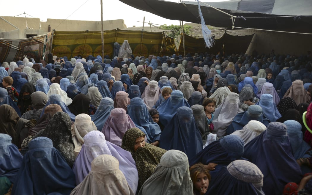 Women with their children wait to receive a food donation from the Afterlife foundation during Ramadan in Kandahar on April 27, 2022.