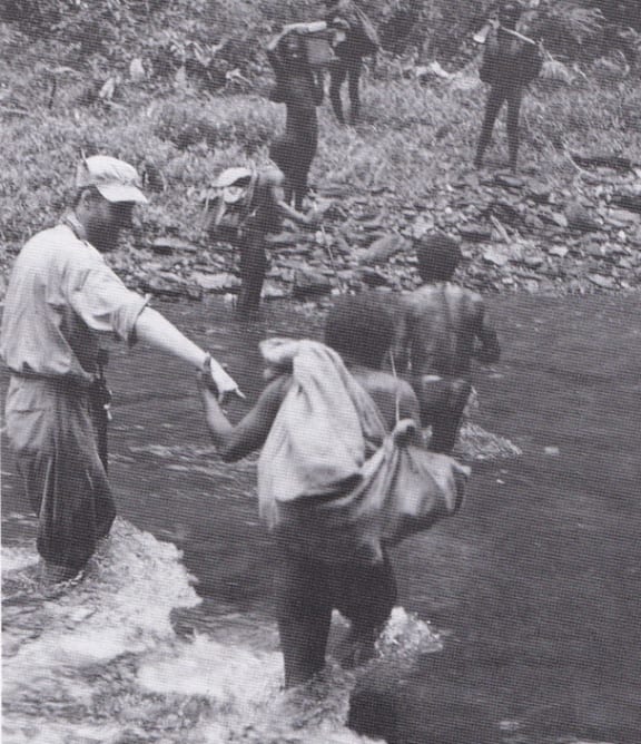 A member of the Dani tribe hangs on to Philip Temple for balance as he embarks on the first Yehlimeh trek.
