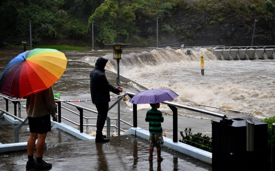 Residents from the neighbourhood watch the over flowing Parramatta river during heavy rain in Sydney on March 20, 2021, amid mass evacuations being ordered in low-lying areas along Australia's east coast as torrential rains caused potentially "life-threatening" floods