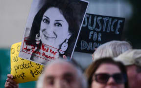 Protesters holding a photo of killed reporter Daphne Caruana Galizia gather outside Parliament in Valletta, Malta, on 26 November.