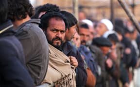 Afghan men stand in queues to receive food aid from a non-governmental organisation (NGO) in Kabul on 25 December, 2022. Several foreign aid groups that day announced they were suspending their operations in Afghanistan after the country's Taliban rulers ordered all NGOs to stop women staff from working.